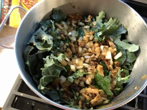 Kale cooking in pot with bacon and onions